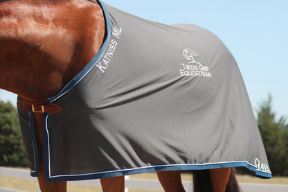 Horse wearing a custom gray scrim sheet with 'Twelve Club Equestrian' ebroidered logo, along with name and horse name embroidered. 
